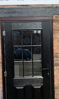 Black wooden door with nine glass panes set in a red brick building facade