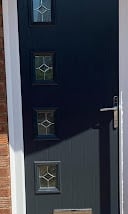 Dark blue front door with three brass door handles and a door frame against a white wall
