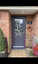 Dark blue front door with gold number 10 on a red brick house entrance with planters and ivy