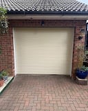 White garage door on brick house with tiled roof and paved driveway