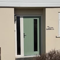 Modern green entrance door with white frame on beige building exterior wall