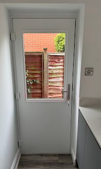 White door with window pane showing red brick exterior and garden view