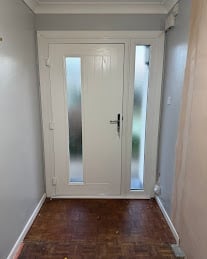 Double white doors with frosted glass panels in a foyer with gray walls and dark hardwood flooring