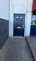 A dark blue arched doorway with fanlight on a white-walled building exterior with surrounding street elements