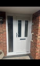 White front door with glass panel on brick house entrance with porch canopy