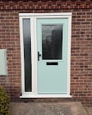 Light blue front door with glass panel on brick house exterior