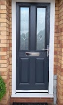 Black front door with glass panels on a brick house with white frame and trim