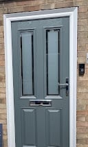 Teal blue traditional door with six panels set in a brick wall frame