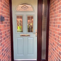 Light blue front door with fanlight and panels set in a brick archway entrance