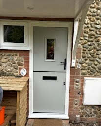 White entrance door with small window on brick and stone building facade