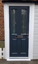 Dark blue front door with glass panes on a brick house exterior
