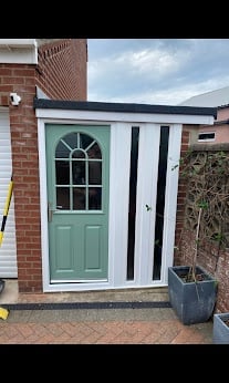 A modern shed with mint green door and white striped walls attached to a brick house