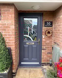 Dark blue front door with glass panel on brick house exterior, decorated with wreath and number 10