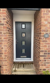 Dark blue front door with glass panels set in a recessed brick archway entrance
