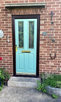 Light blue door with glass panels set in black frame on red brick building with concrete step