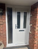 White front door with glass panels on a brick home entrance