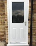 White composite front door with glass panel mounted on brick wall exterior of home